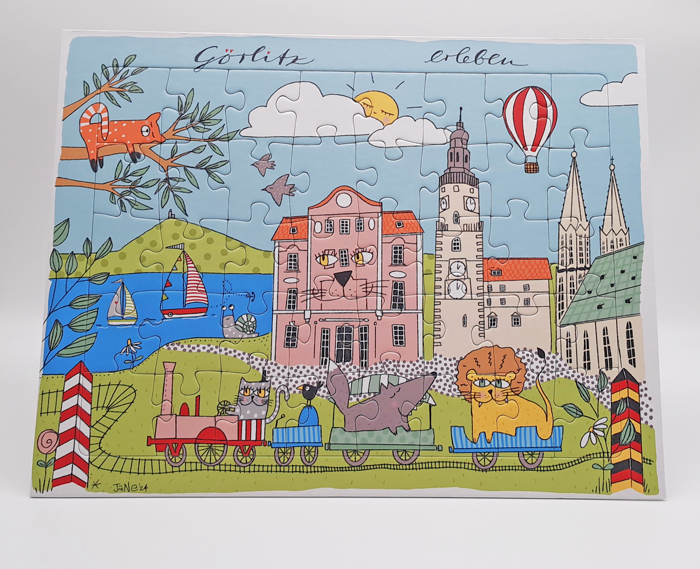 Auf dem Puzzle ist ein butes, gezeichnets Motiv mit Görlitzer Sehenswürdigkeiten und Kindgerechten Details. Von der Landeskrone und dem Berzdorfersee, über das Naturkundemuseum, dem Rathausturm zur Peter- und Paulkirche. Selbst die Parkeisenbahn, die eine