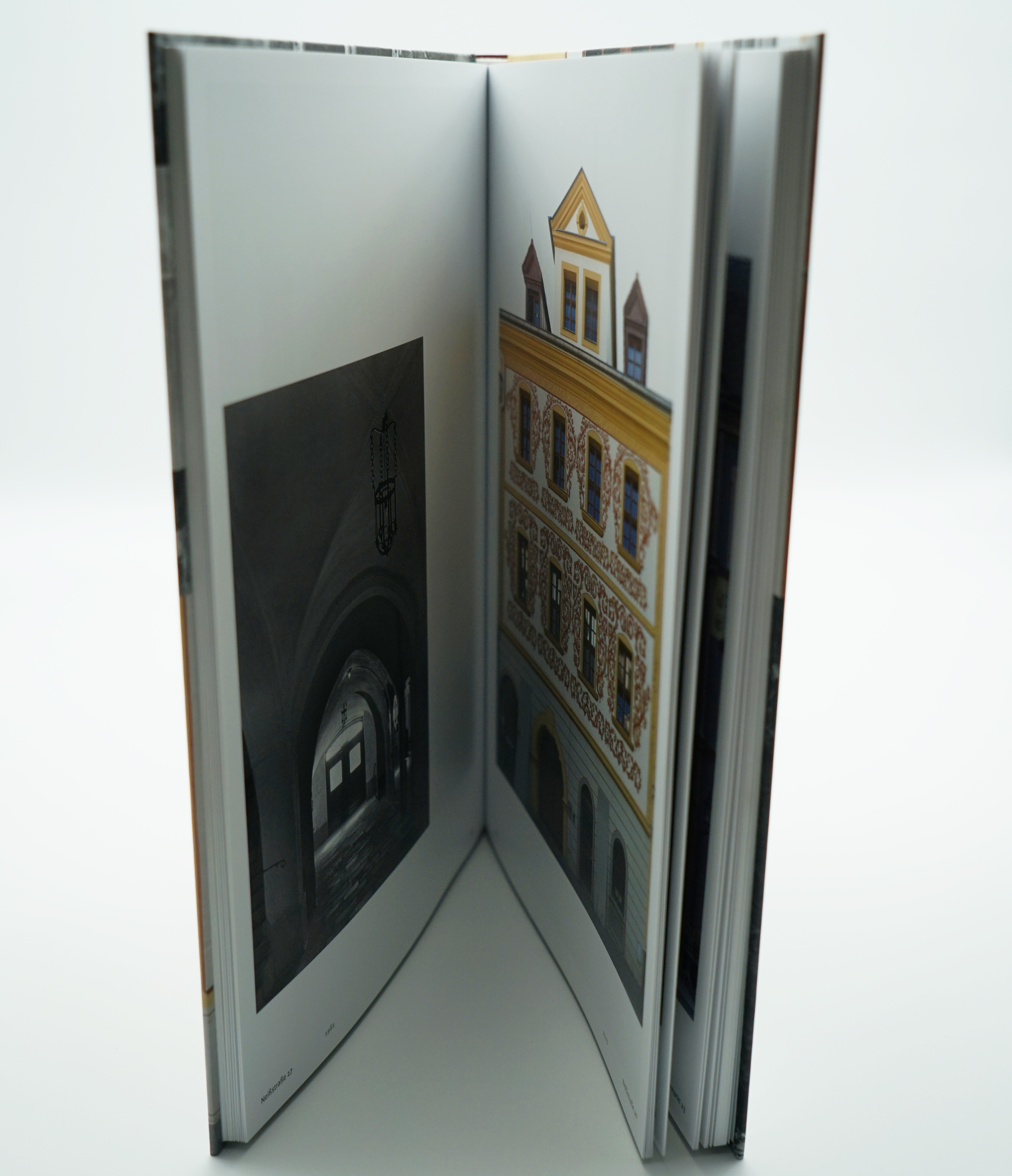 Das buch ist aufgestellt und man erkennt wie dick das Buch ist und sieht seitlich auf eine Doppelseite mit Fotografien.