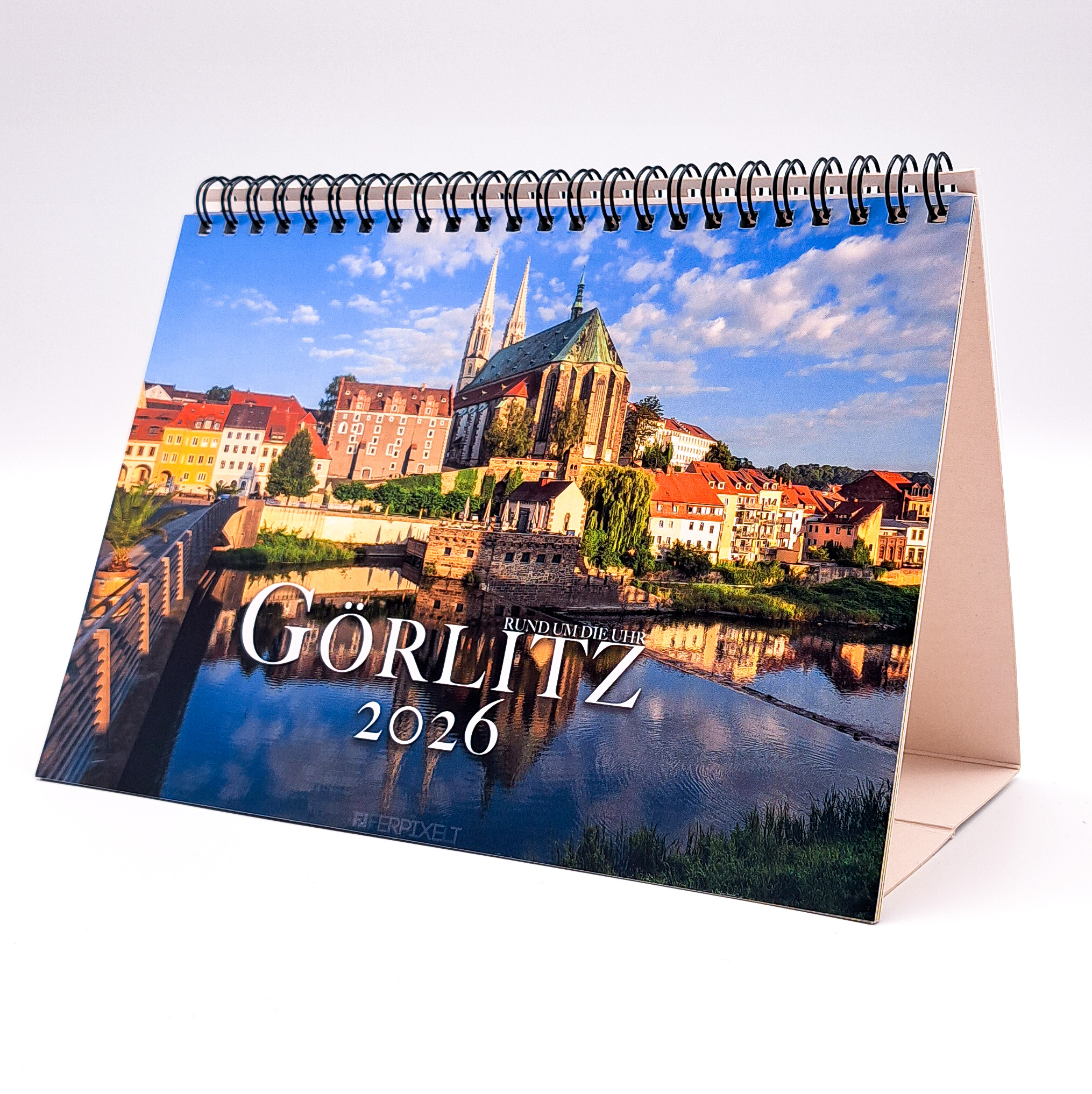 Auf der Titelseite des Tischkalenders 2026 "Görlitz Rund um die Uhr" ist die Neiße mit der Altstadtbrücke zu sehen. Die Peterkirche wird von der Morgensonne angestrahlt.