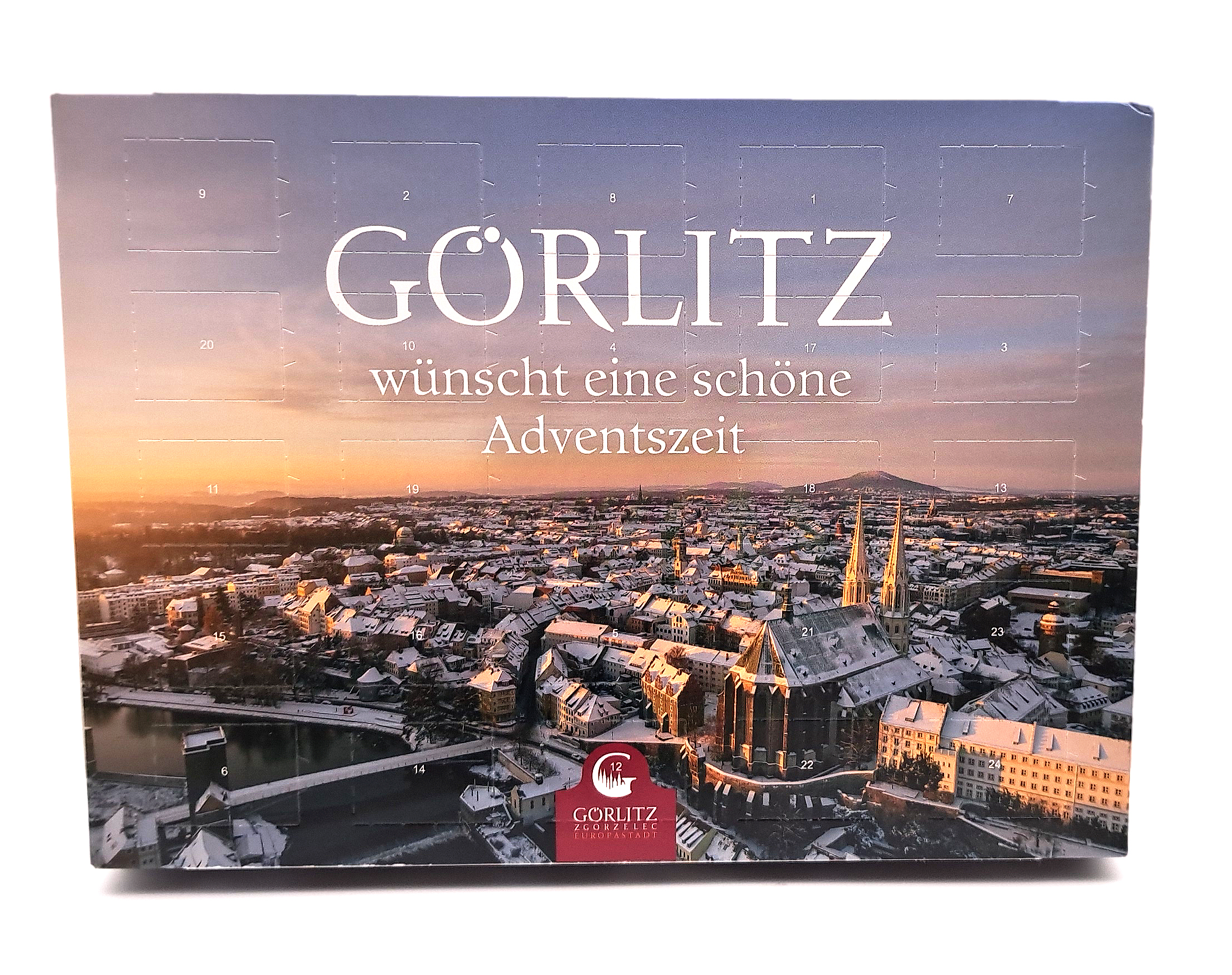 Der Adventskalender von 2025 hat auf der Titelseite ein winterliches Stadtpanorama bei Sonnenaufgang aus der Vogelperspektive. 