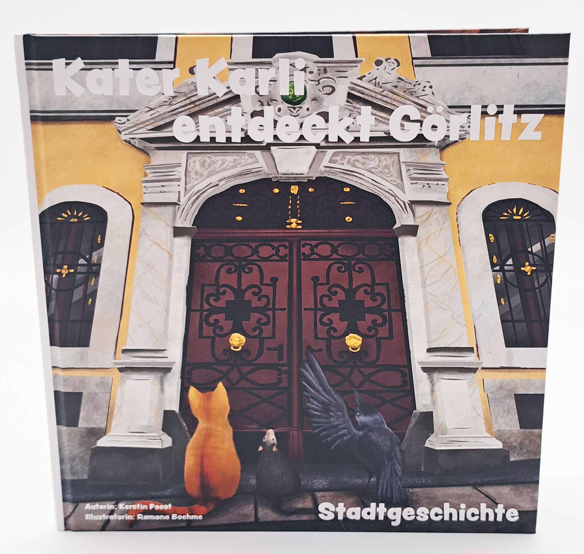 Vorderseite von Kater Karli endeckt Görlitz Stadtgeschichte auf der Titelseite des Buches Kater Kali entdeckt Görlitz Stadtgeschichte sieht man die Tür vom Barockhaus und davor sitzen mit dem Rücken zum Leser von links Kater Karli, die Maus und der Rabe.