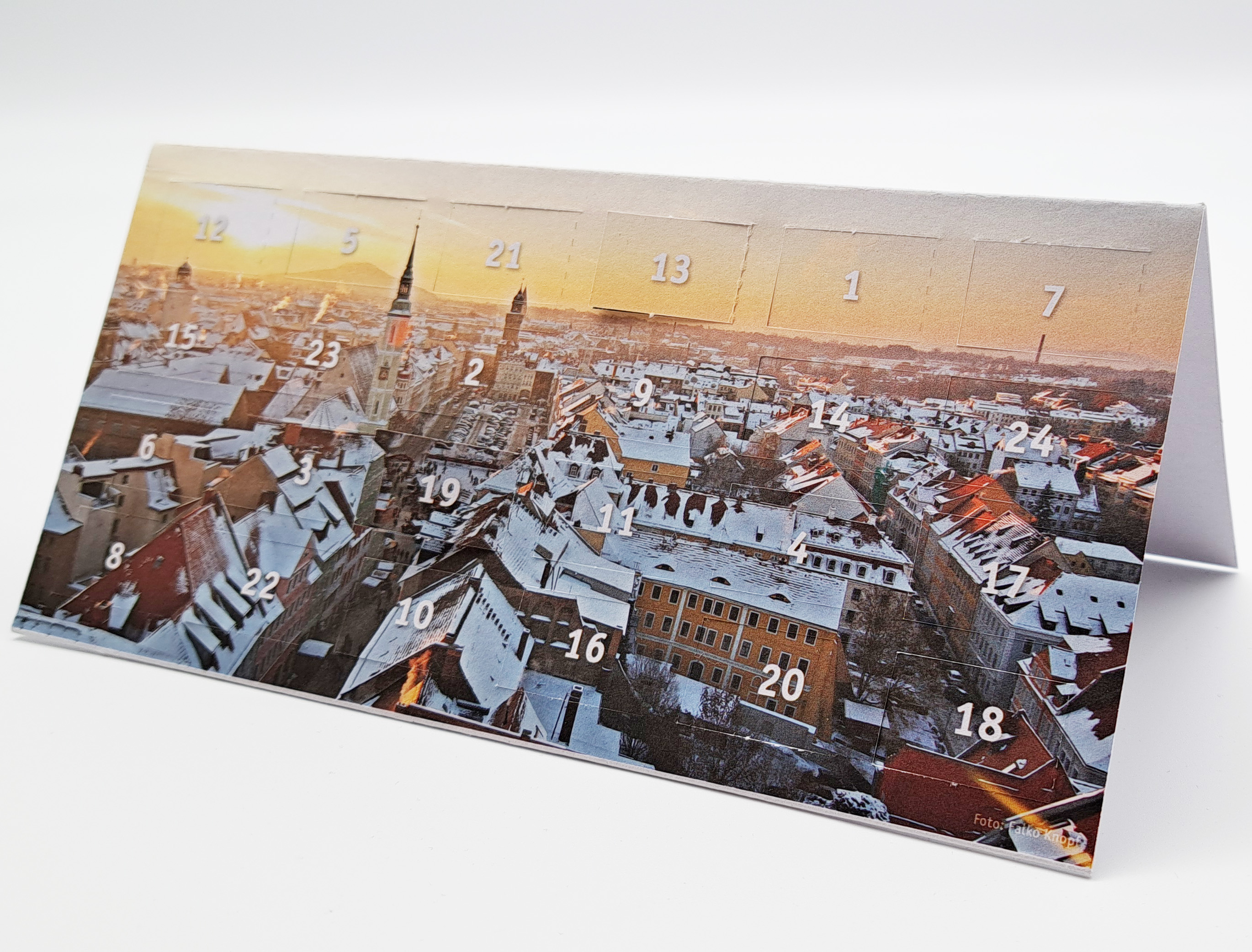 Eine Karte, im Format DIN lang, steht aufgeklappt auf der langen Seite auf einem weißen Untergrund. Auf der Titelseite sieht man ein Fotomotiv von Görlitz. Es wurde in der Vogelperspektive fotografiert (aufgenommen vom Rathausturm) und zeigt die verschnei