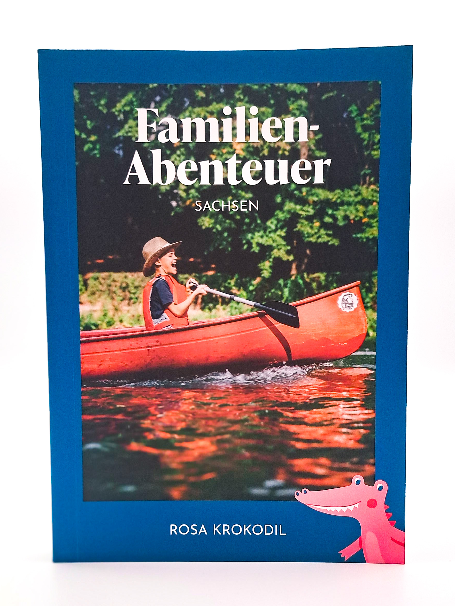 Auf dem Titelbild ist ein Junge im Kanu zu sehen, das Paddel gerade noch nicht im Wasser. Unten rechts ist wieder das freundliche, Comic-Krokodil in rosa zu sehen.