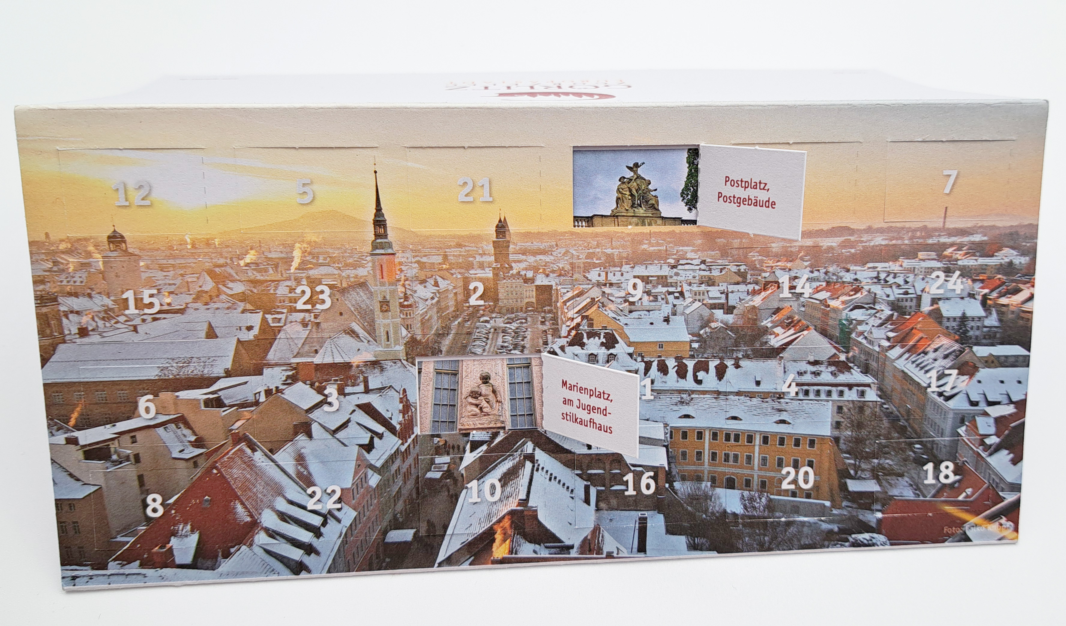 Titelseite der Adventskalender-Klappkarte mit 2 offenen Türchen Die Titelseite ist zu sehen, und hier sind zwei Türchen geöffnet. Beide Motive sind zu erkennen und in dem aufgeklappten Türchen steht in roter Schrift, was auf dem Foto zu sehen ist.