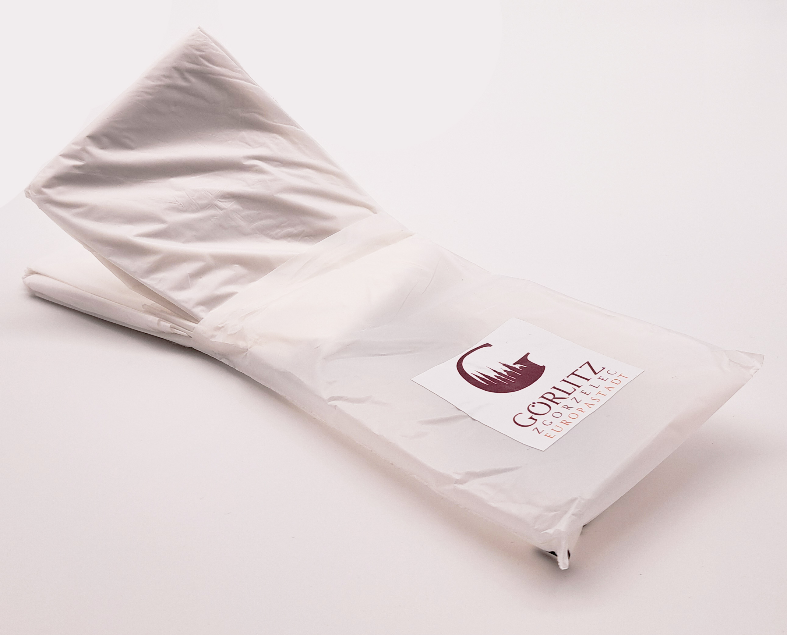 geöffnete Regenponchoverpackung der gefaltete Regenponcho wird etwas aus der Verpackung rausgezogen.