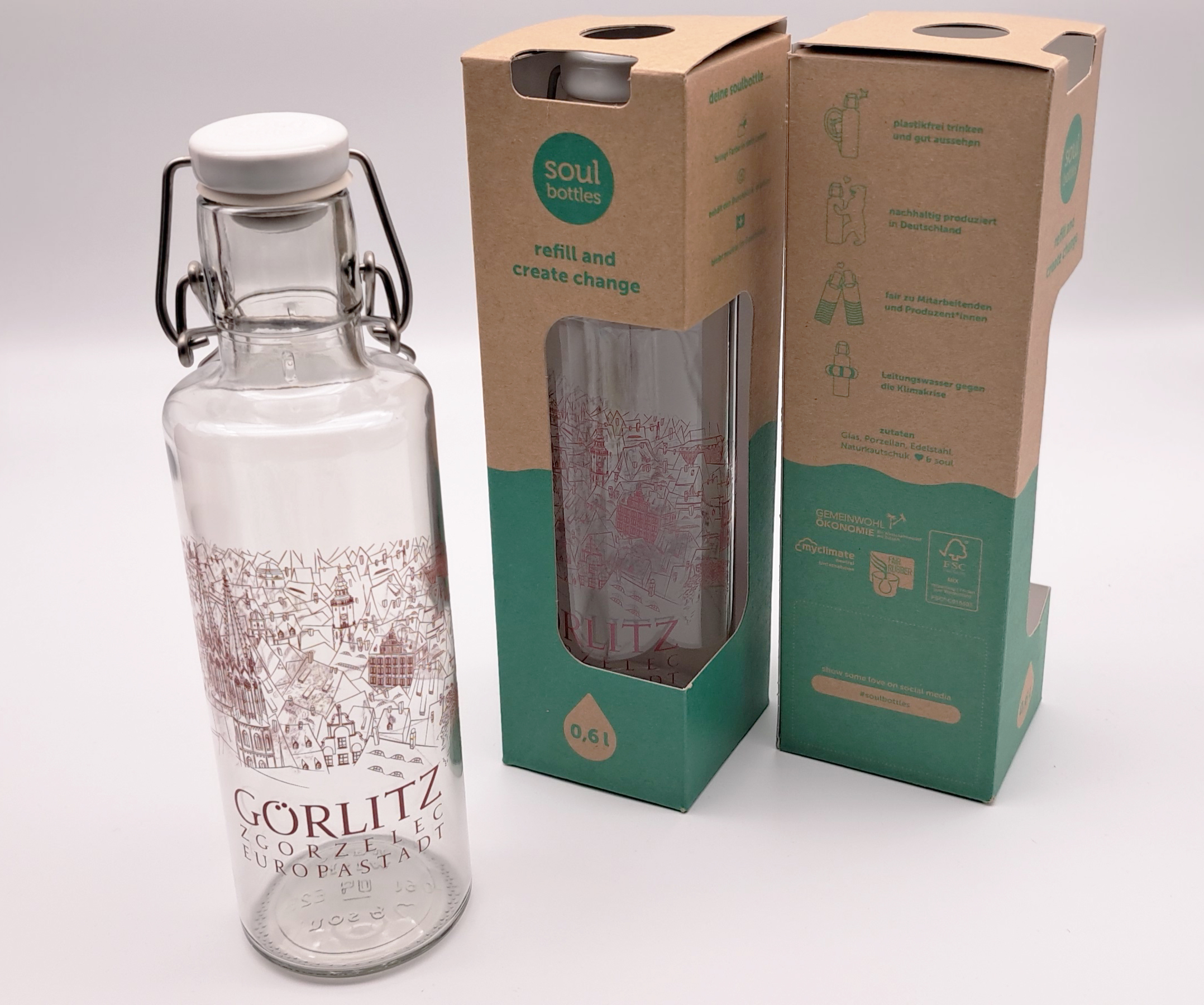 links ist eine Glasfalsche mit Görlitz-Motiv  zu sehen. Mittig ist die gleich Flasche in der Papierverpackung zu sehen und rechts ist diese Verpackun nochmal gedreht zu sehen.