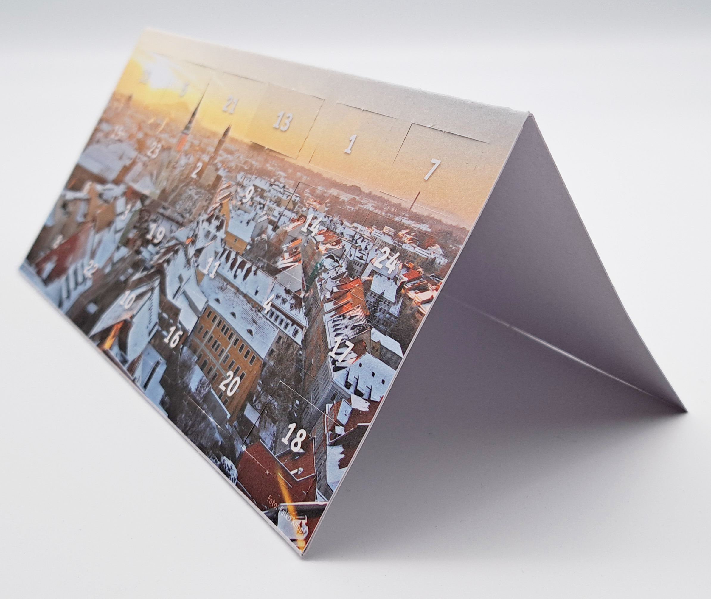 Adventskalender-Klappkarte nach links gedreht Eine Karte, im Format DIN lang, steht aufgeklappt auf der langen Seite auf einem weißen Untergrund. Die Karte ist nach links gedreht.Auf der Titelseite sieht man ein Fotomotiv von Görlitz. Es wurde in der Vogelperspektive fotografiert (aufgenommen vom Rat
