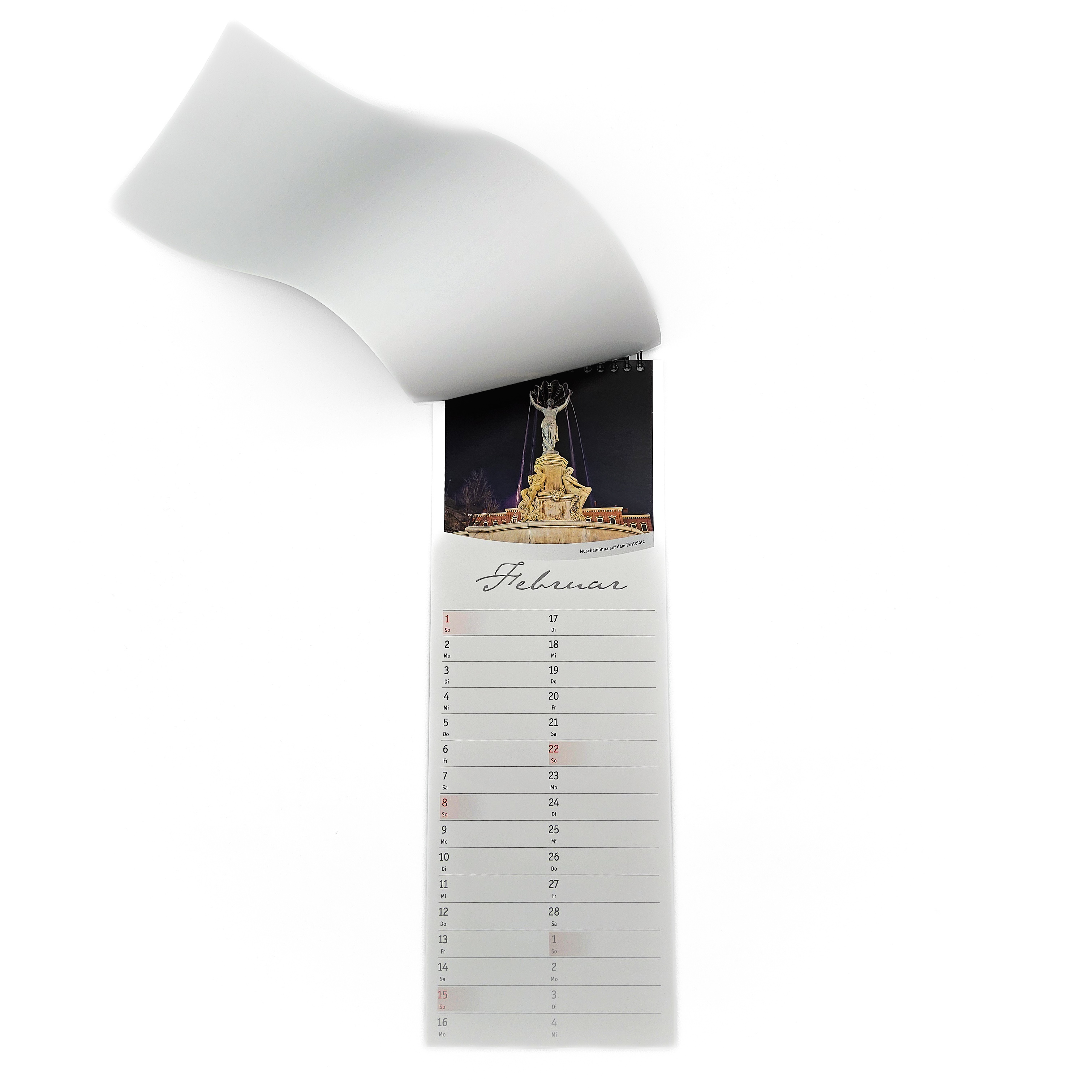 Der Küchenkalender ist aufgeschlagen. Man sieht den Monat Januar. Auf dem Bild ist die Muschelminna mit der Winterbeleuchtung über der Holzverkleidung zu sehen.