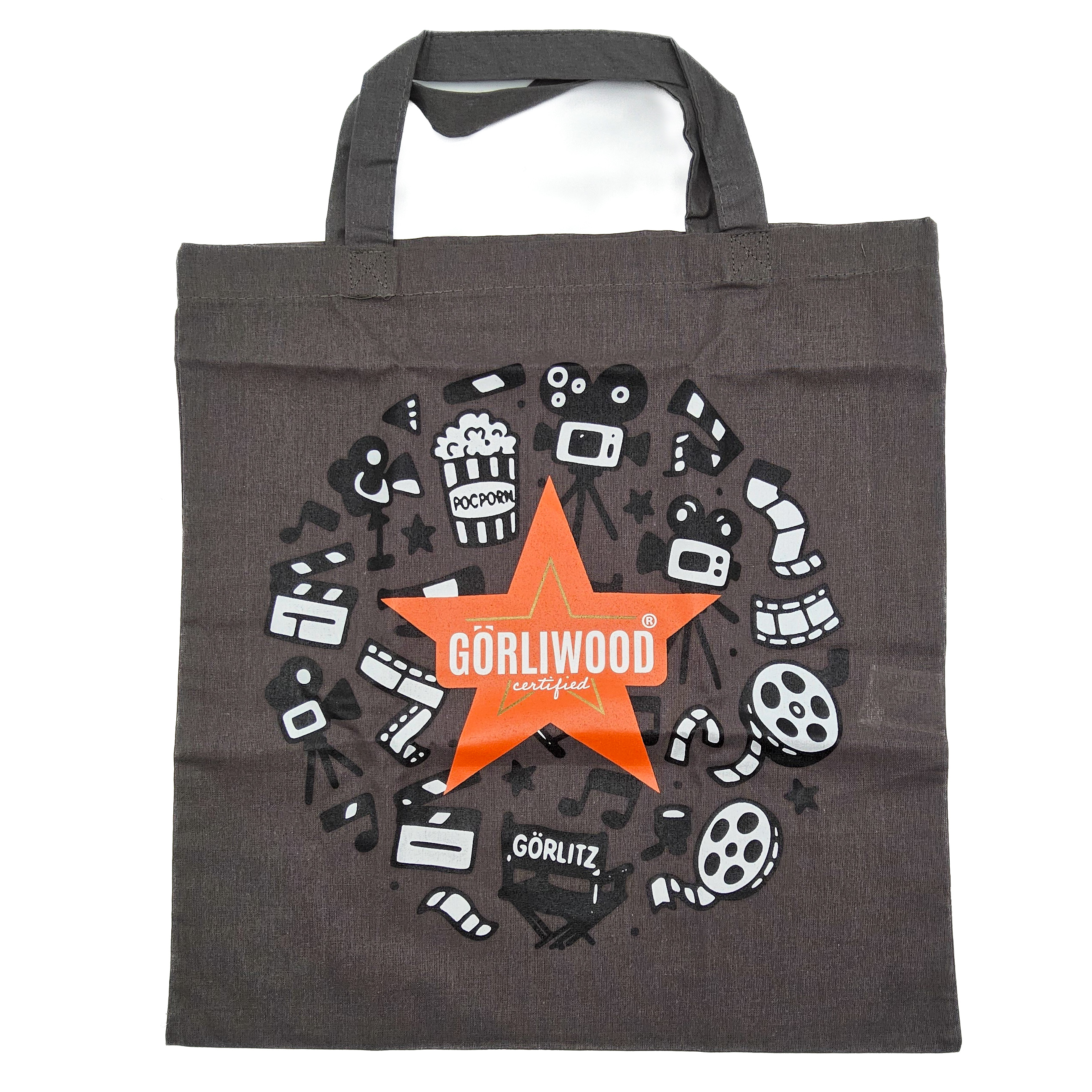 Der graue Stoffbeutel hat einen kurzen Henkel. Mittig ist der fünfzackige, orangefarbene Görliwoodstern zu sehen. Dahinter sind kreisförmig verschiedene Motive aus dem Bereich Film zu erkennen.