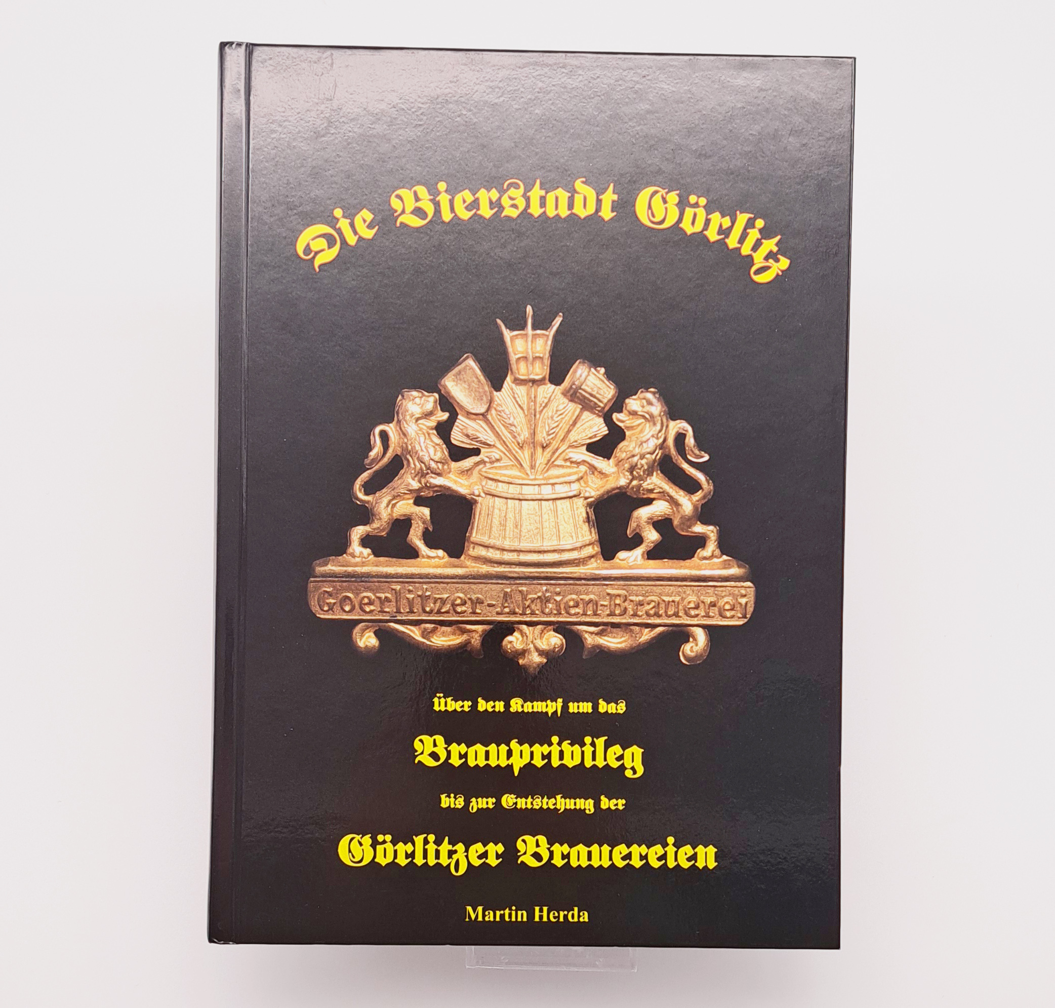 Das Cover des Buches die Bierstadt Görlitz zeigt einen Bornzeguss. Über die gesamte Breite dieser Plastik steht Görlitzer Aktien Brauerei, darüber ist mittig ein Holzfass, darin ist neben der Gerste auch das Brau-Werkzeug zu erkennen. Links und rechts ste
